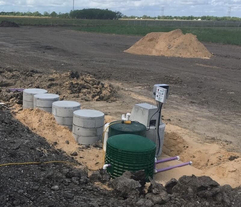 Septic tank installation in progress with concrete tanks and green storage container on jobsite